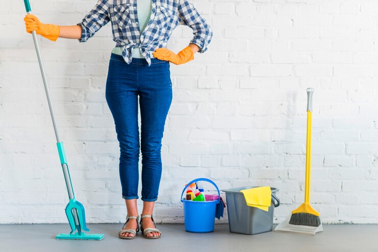 woman-standing-front-brick-wall-with-cleaning-equipments_23-2147916547